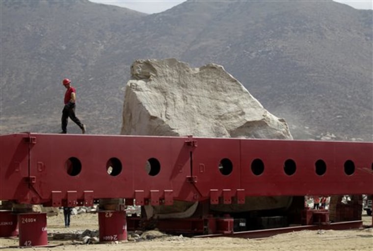 In this Sept. 22, 2011 photo, Joe Schofield, left, walks along the giant steel beam built to support a 340-ton rock as he and other workers prepare to transport the rock from Riverside County to the Los Angeles County Museum of Art at Stone Valley Materials in Riverside, Calif. 